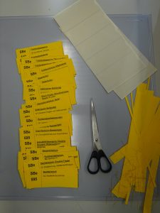 Neu ausgedruckte Becshriftungsetiketten für die Archivboxen werden zugeschnitten