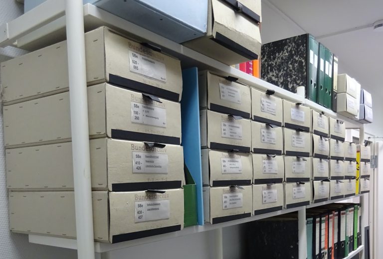 Archivboxen mit Broschüren im Vorablage-Regal