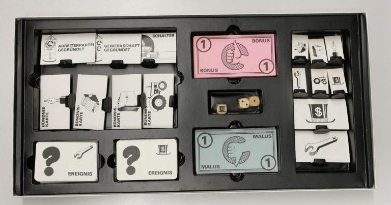 Spielkarten, Spielgeld un Würfel in einem Spielekarton
