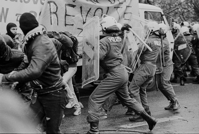 Polizeibeamte mit Schutzschilden und Schlagstöcken prügeln auf vermummte Demonstrierende ein, 20.12.1986